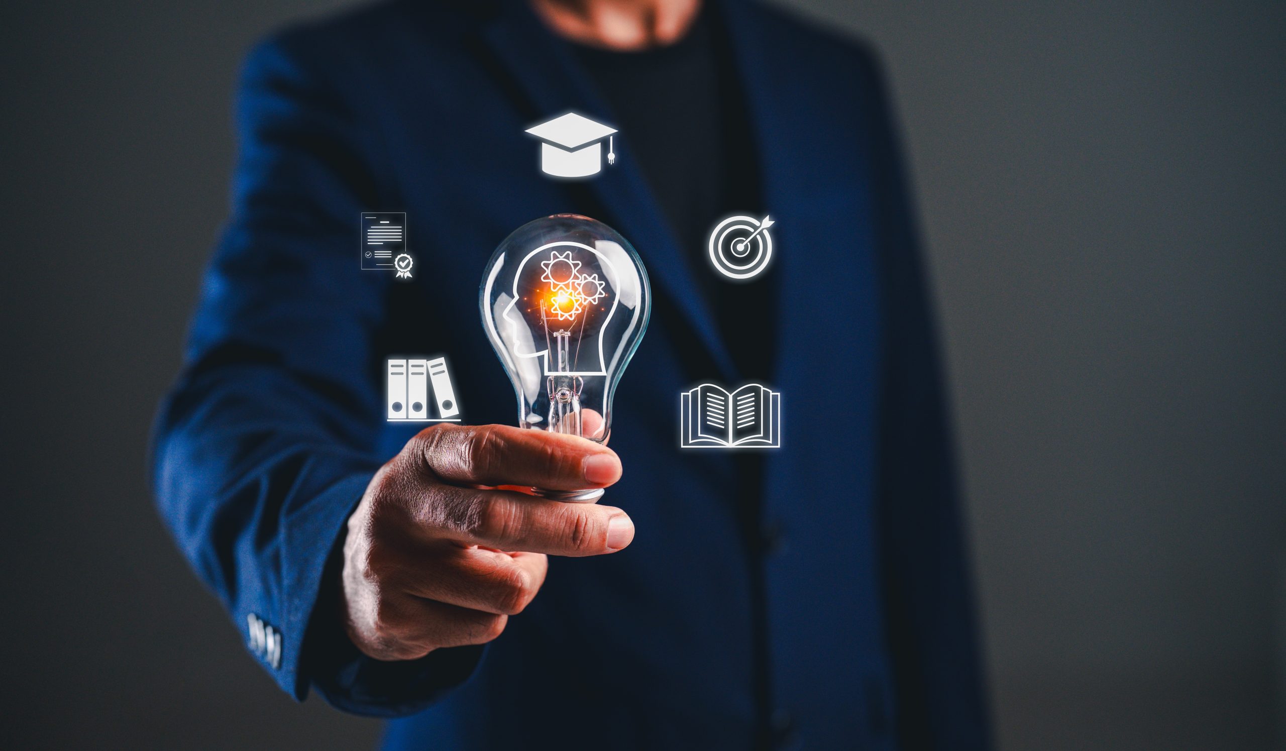 Hand holding lightbulb surrounded by educational icons.